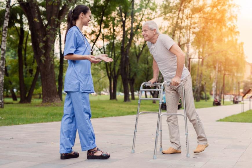 young nurse is standing park helps elderly man